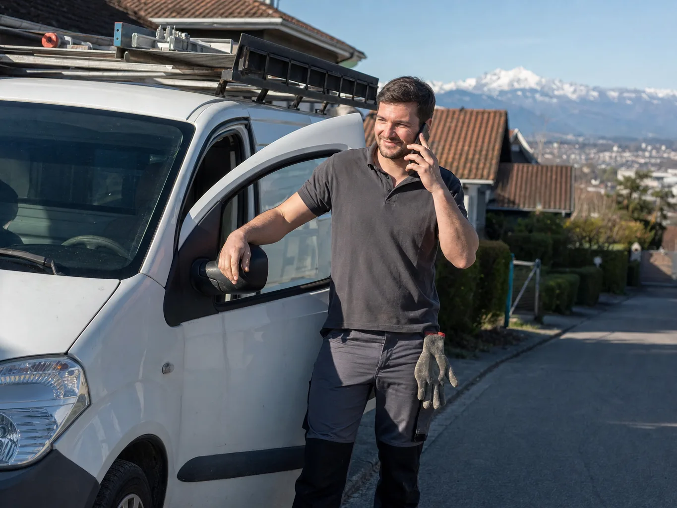 Artisan couvreur au téléphone à côté de sa camionnette de chantier, dans une rue de Pau