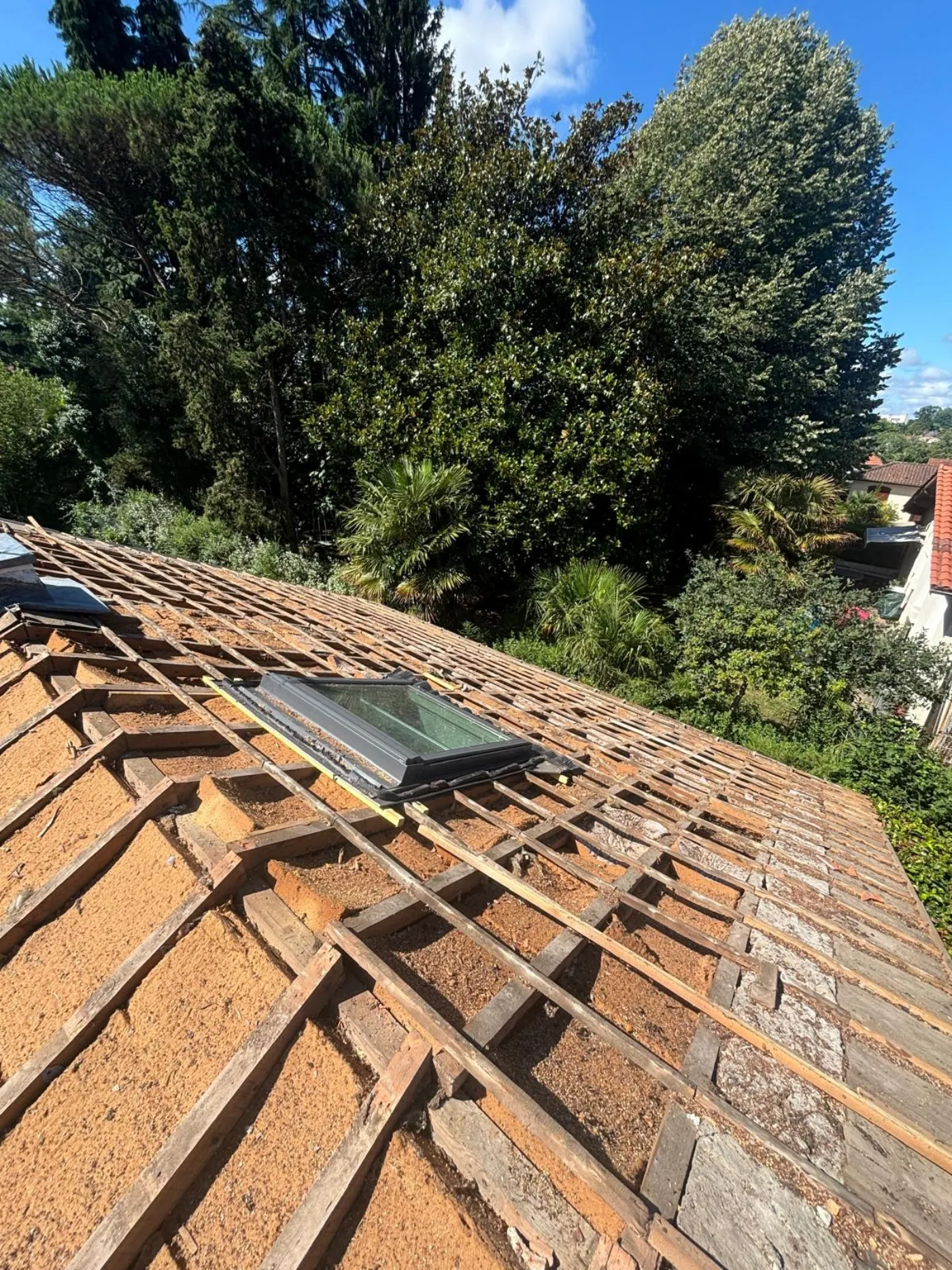 Toiture en cours de dépose, tuiles anciennes retirées et liteaux apparents
